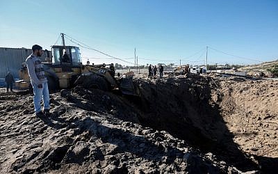 Des Palestiniens nettoient les décombres sur le site d'une frappe israélienne après d'un port maritime en construction à proximité de Khan Younès, dans le sud de la bande de Gaza, le 9 mars 2018 (Crédit : SAID KHATIB / AFP)