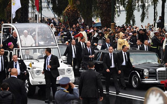 Le roi Mohammed VI, à droite, salue la foule depuis sa voiture lors de l'arrivée du pape Français dans la papamobile lors de l'arrivée du souverain pontife au Maroc, le 30 mars 2019 (Crédit : Alberto Pizzoli/AFP)