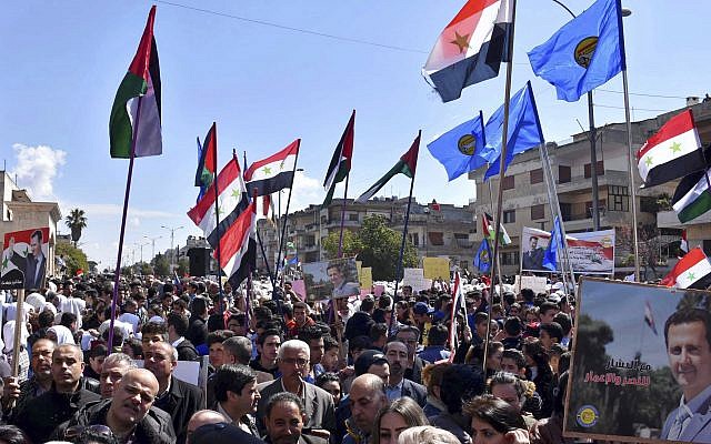 Des Syriens brandissent des portraits de Bashar el Assad durant une manifestation contre la reconnaissance de la souveraineté israélienne sur le plateau duGolan par Donald Trump, le 26 mars 2019. (Crédit : SANA via AP) Des Syriens brandissent des portraits de Bashar el Assad durant une manifestation contre la reconnaissance de la souveraineté israélienne sur le plateau duGolan par Donald Trump, le 26 mars 2019. (Crédit : SANA via AP)