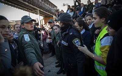 Des garde-frontières aident les membres des Femmes du mur à partir après avoir tenté de mener à bien les prières du mois, alors que des milliers de femmes ultra-orthodoxes s'opposent à elles au mur Occidental, dans la Vieille Ville de Jérusalem, le 8 mars 2019 (Crédit : Hadas Parush/Flash90)