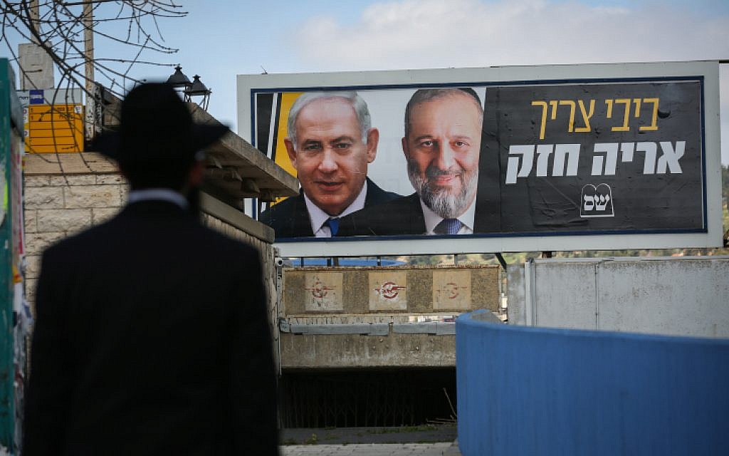 Un Juif ultra-orthodoxe devant un panneau d'affichage avec des photos du Premier ministre Benjamin Netanyahu et du chef du Shas Aryeh Deri, dans le cadre de la campagne électorale Shas, à Safed, le 10 mars 2019. (David Cohen/Flash90) Un Juif ultra-orthodoxe devant un panneau d'affichage avec des photos du Premier ministre Benjamin Netanyahu et du chef du Shas Aryeh Deri, dans le cadre de la campagne électorale Shas, à Safed, le 10 mars 2019. (David Cohen/Flash90)