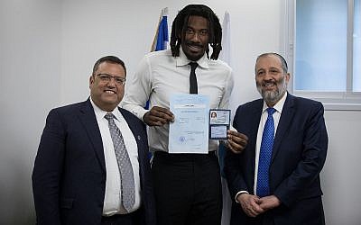 Le joueur de basket Amar'e Stoudemire (en centre) brandit sa carte d'identité israélienne aux côtés de ministre de l'Intérieur Aryeh Deri et du maire de Jérusalem Moshe lion, le 13 mars 2019. (Crédit : Hadas Parush/Flash90)