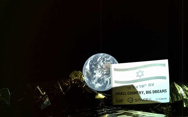 La photo prise par la sonde Bereshit : une plaque installée sur la paroi externe de la sonde arbore le drapeau national israélien et les phrases "Am Yisrael Hai" (Vive le peuple d'Israël) et "Petit pays, grands rêves", avec le globe terrestre en arrière plan. (Crédit :SpaceIL/IAI)