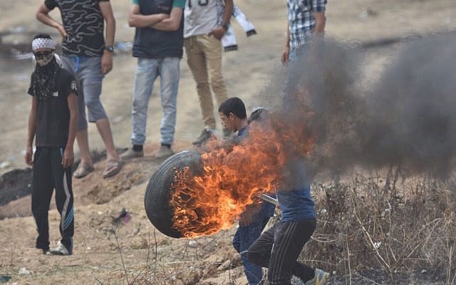 Des Palestiniens lancent des pneus enflammés sur la barrière de sécurité de Gaza lors de la sixième manifestation "Marche du retour", le 4 mai 2018. (Armée israélienne) Des Palestiniens lancent des pneus enflammés sur la barrière de sécurité de Gaza lors de la sixième manifestation "Marche du retour", le 4 mai 2018. (Armée israélienne)