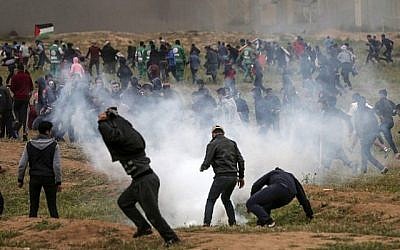 Des émeutiers palestiniens courent se mettre à l’abri de gaz lacrymogène tirés par l’armée israélienne lors des affrontements qui ont suivi une manifestation marquant le premier anniversaire des manifestations violentes de la "Marche du retour", à proximité de la frontière avec Israël à l’est de Gaza ville le 30 mars 2019. (Mahmud Hams/AFP)
