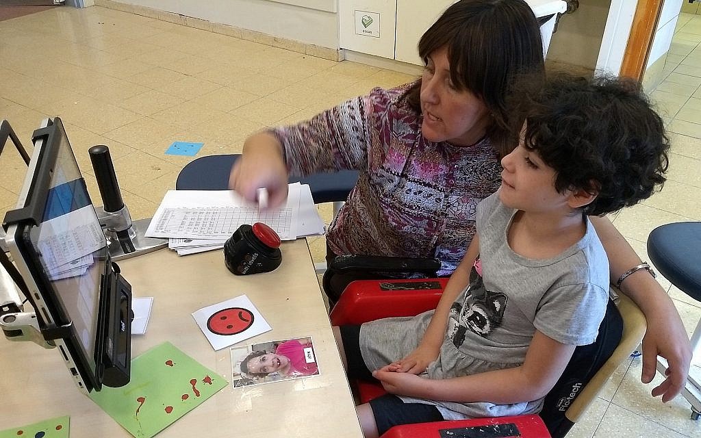 Ayala, 11 ans, une élève atteinte d'un trouble cognitif, communique via un écran d'ordinateur avec son enseignante, Rivka Dimant, dans une école d'Aleh Negev, un campus pour Israéliens souffrant de handicaps, le 25 octobre 2018. (Crédit : Ben Sales via JTA) Ayala, 11 ans, une élève atteinte d'un trouble cognitif, communique via un écran d'ordinateur avec son enseignante, Rivka Dimant, dans une école d'Aleh Negev, un campus pour Israéliens souffrant de handicaps, le 25 octobre 2018. (Crédit : Ben Sales via JTA)