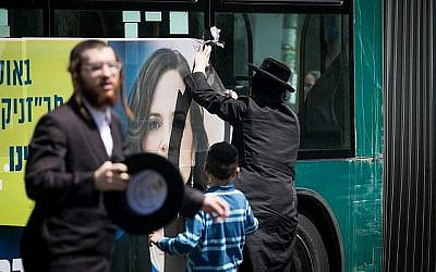 Des manifestants ultra-orthodoxes vandalisent une affiche électorale de la députée Rachel Azaria, candidate à la mairie de Jérusalem, dans le quartier de Mea Shearim de Jérusalem le 26 juillet 2018. (Yonatan Sindel/Flash 90) Des manifestants ultra-orthodoxes vandalisent une affiche électorale de la députée Rachel Azaria, candidate à la mairie de Jérusalem, dans le quartier de Mea Shearim de Jérusalem le 26 juillet 2018. (Yonatan Sindel/Flash 90)