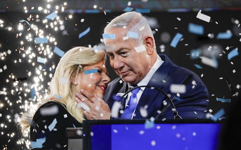 Le Premier ministre israélien embrasse son épouse Sara durant son apparition devant les partisans au siège du parti du Likud dans la ville côtière de Tel Aviv, la nuit des élections, le 10 avril 2019 (Crédit : Thomas COEX / AFP)