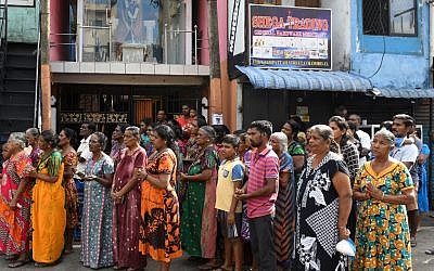 Des Sri-lankais en deuil assistent aux trois minutes de silence en hommage aux victimes des attaques survenues le dimanche de Pâques. 23 avril 2019. (Crédit photo : LAKRUWAN WANNIARACHCHI / AFP)