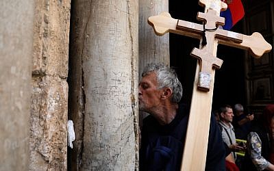 Un pèlerin chrétien orthodoxe porte une croix le long de la  Via Dolorosa pour entrer dans l'église du Saint sépulcre dans la Ville ville de Jérusalem à l'occasion de la procession orthodoxe du vendredi saint, le 26 avril 2019 (Crédit :  GALI TIBBON / AFP)