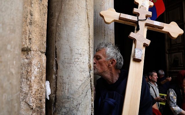 Un pèlerin chrétien orthodoxe porte une croix le long de la  Via Dolorosa pour entrer dans l'église du Saint sépulcre dans la Ville ville de Jérusalem à l'occasion de la procession orthodoxe du vendredi saint, le 26 avril 2019 (Crédit :  GALI TIBBON / AFP)