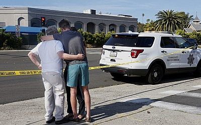 Des gens se réconfortent mutuellement devant la synagogue Habad de Poway, en Californie, qui se trouve de n'autre côté de la rue, après une fusillade, le 27 avril 2019 (Crédit : SANDY HUFFAKER / AFP)