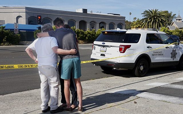 Des gens se réconfortent mutuellement devant la synagogue Habad de Poway, en Californie, qui se trouve de n'autre côté de la rue, après une fusillade, le 27 avril 2019 (Crédit : SANDY HUFFAKER / AFP)
