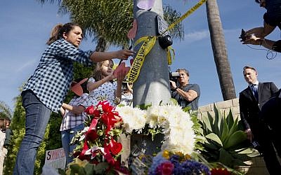 Une femme et une jeune fille placent des papiers sur un petit mémorial dressé face à la synagogue Habad de Poway, en Californie, après une fusillade, le 27 avril 2019 (Crédit : SANDY HUFFAKER / AFP)