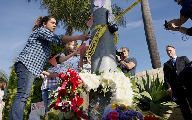 Une femme et une jeune fille placent des papiers sur un petit mémorial dressé face à la synagogue Habad de Poway, en Californie, après une fusillade, le 27 avril 2019 (Crédit : SANDY HUFFAKER / AFP) Une femme et une jeune fille placent des papiers sur un petit mémorial dressé face à la synagogue Habad de Poway, en Californie, après une fusillade, le 27 avril 2019 (Crédit : SANDY HUFFAKER / AFP)