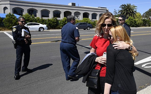 Jessica Parks, à droite, réconforte Tina White aux abords de la synagogue de Poway, en Californie, après une fusillade, le 27 avril 2019 (Crédit : AP/Denis Poroy)