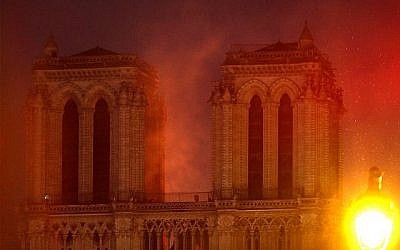 Les flammes illuminent le ciel alors que la cathédrale Notre-Dame brûle, le 15 avril 2019. (AP Photo / Thibault Camus)