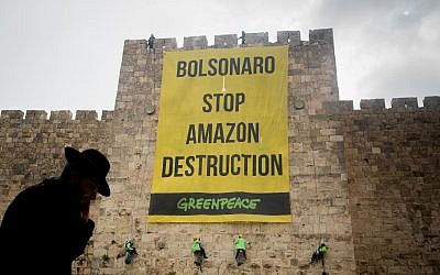 Des militants de Greenpeace descendent en rappel les murs de la Vieille Ville de Jérusalem, lors d'une manifestation le 1er avril 2019, pour accrocher une banderole disant "Bolsonaro Stop Amazon Destruction" pendant la visite du président brésilien Jair Bolsonaro en Israël. (Yonatan Sindel/Flash90)