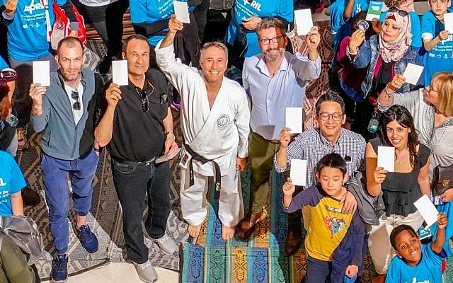 Des participants de la "Journée du carton blanc" - la "Journée internationale du sport au service du développement et de la paix" organisée par les Nations unies - s'est tenue pour la première fois en Israël le 7 avril 2019, brandissent leur carte blanche. (Crédit : Jordan Polevoy)