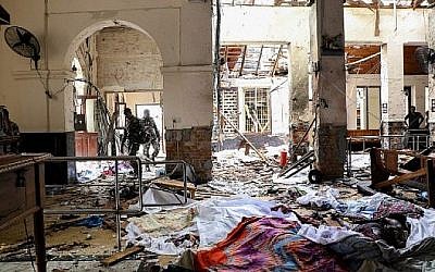 Des membres de services de sécurité du Sri Lanka marchent à côté de cadavres au sol parmi les débris de l'explosion au sanctuaire St Anthony, après l'exposition dans l'église à Kochchikade à Colombo, le 21 avril 2019. (ISHARA S. KODIKARA/ AFP)