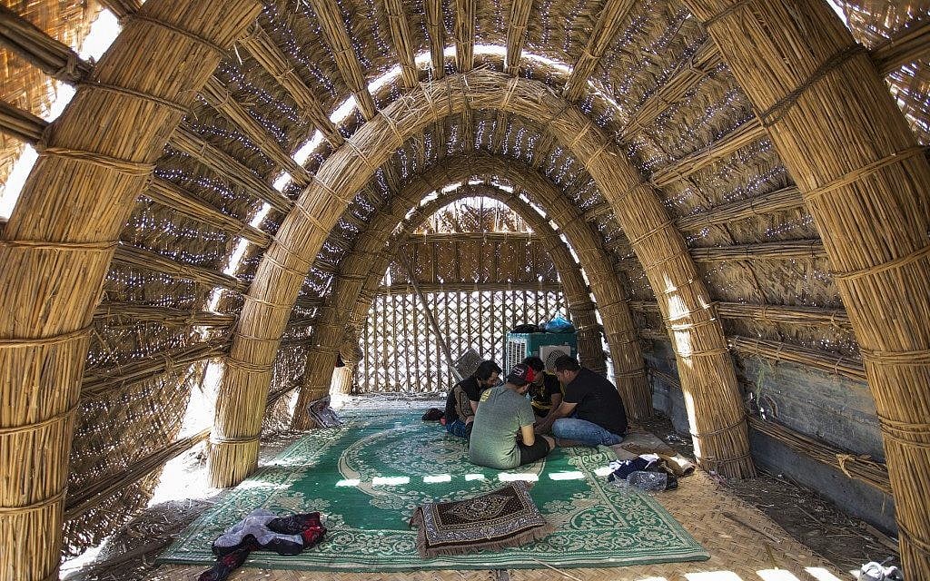 Des touristes assis dans une maison maison flottante faite de roseaux et de palmes de dattiers, en Irak, le 29 mai 2019. (Crédit : Hussein FALEH / AFP) Des touristes assis dans une maison maison flottante faite de roseaux et de palmes de dattiers, en Irak, le 29 mai 2019. (Crédit : Hussein FALEH / AFP)