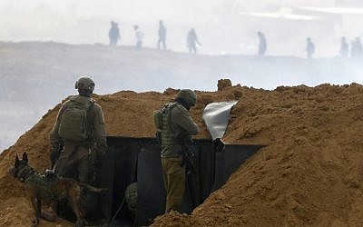 Des soldats israéliens se rassemblent sur une position le long de la frontière avec la bande de Gaza, près du kibboutz de Nahal Oz, au sud d'Israël, le 30 mars 2019, alors que des Palestiniens (en arrière-plan) manifestent pour le premier anniversaire des manifestations de "La Marche du retour". (Jack Guez/AFP)