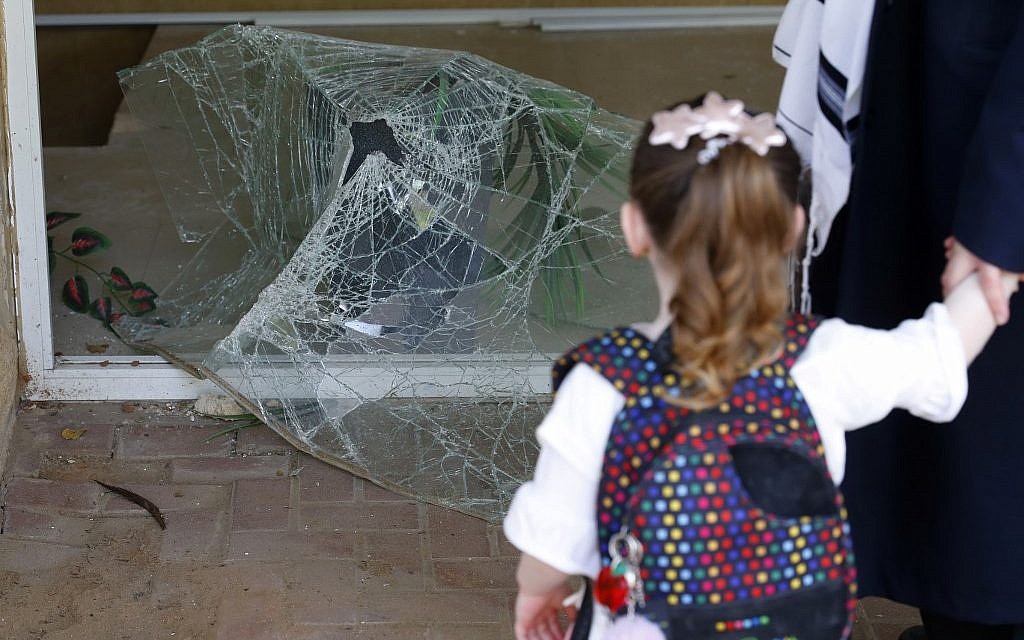 Une fillette israélienne regarde une vitre brisée à l'entrée d'un immeuble endommagé par une frappe de roquettes depuis la bande de Gaza, dans la ville d'Ashdod, dans le sud d'Israël, le 6 mai 2019. (Jack Guez/AFP)