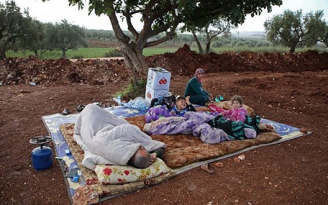 Des Syriens dans un champ près d'un camp pour les personnes déplacées dans le village d'Atmé, dans la province d'Idlib contrôlée par les djihadistes, le 8 mai 2019. (Crédit : Aaref WATAD / AFP) Des Syriens dans un champ près d'un camp pour les personnes déplacées dans le village d'Atmé, dans la province d'Idlib contrôlée par les djihadistes, le 8 mai 2019. (Crédit : Aaref WATAD / AFP)