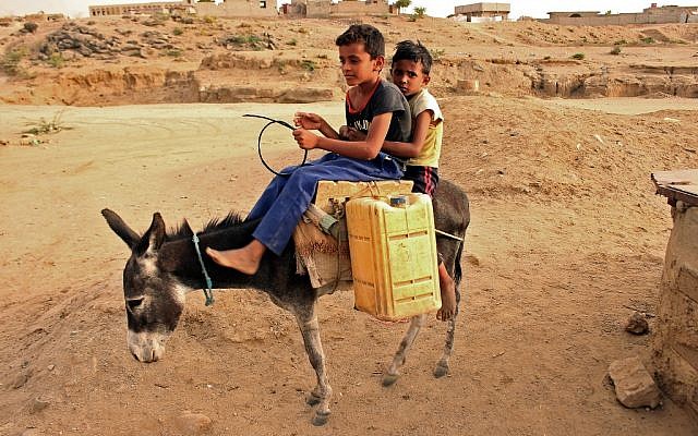 Des enfants yéménites transportent des bidons d'eau dans un camp au nord d'Abs, dans la province de Hajja, le 9 mai 2019; (Crédit : ESSA AHMED / AFP) Des enfants yéménites transportent des bidons d'eau dans un camp au nord d'Abs, dans la province de Hajja, le 9 mai 2019; (Crédit : ESSA AHMED / AFP)
