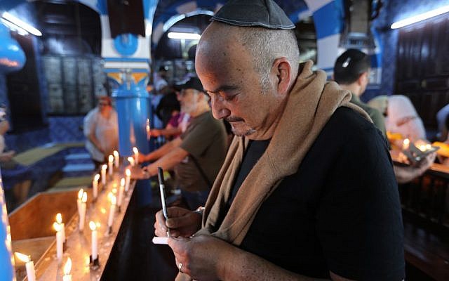 Un pèlerin juif allume une bougie le premier jour du pèlerinage annuel juif à la synagogue de la Ghriba, le plus ancien monument juif construit en Afrique, sur l'île balnéaire de Djerba, en Tunisie, le 22 mai 2019. (Crédit : FATHI NASRI / AFP)