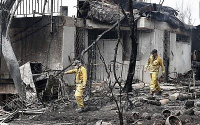 Les soldats du feu israéliens dans une habitation gravement endommagée par un incendie dans le village de Mevo Modiim, dans le centre d'Israël, le 24 mai 2019 (Crédit : JACK GUEZ / AFP)