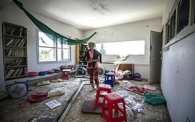 Une femme constate les dégâts causés par une roquette tirée depuis la bande de Gaza qui a touché une maison d'un moshav israélien près de la frontière avec Gaza, le samedi 4 mai 2019. (Crédit : AP / Tsafrir Abayov) Une femme constate les dégâts causés par une roquette tirée depuis la bande de Gaza qui a touché une maison d'un moshav israélien près de la frontière avec Gaza, le samedi 4 mai 2019. (Crédit : AP / Tsafrir Abayov)