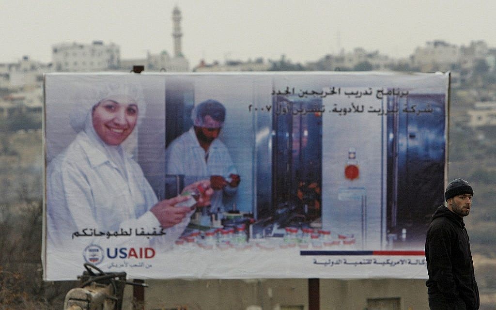Un Palestinien passe devant un panneau de l'USAID dans la ville de Halhoul, en Cisjordanie, en 2007 (Crédit :  AP Photos/Kevin Frayer)
