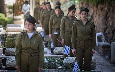Des soldates placent des drapeaux israéliens sur les tombes de soldats au cimetière militaire du mont Herzl, à Jérusalem, le 16 avril 2018, avant Yom HaZikaron, le Jour du souvenir des soldats israéliens tombés au combat. (Hadas Parush/Flash90)