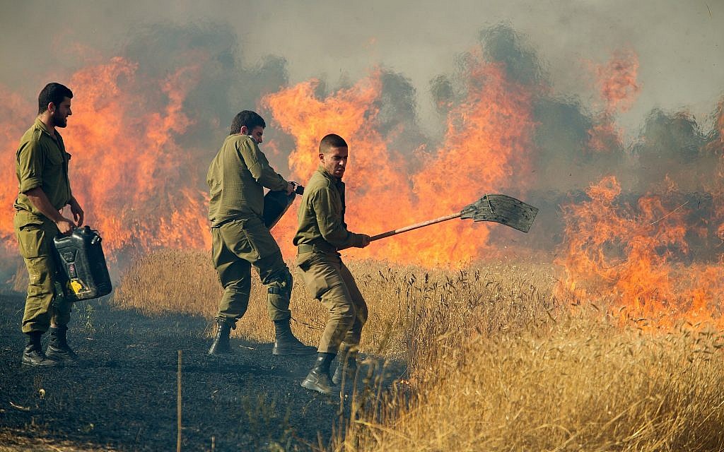 Des soldats israéliens éteignent un incendie dans un champ de Nahal Oz causé par des cerfs-volants incendiaires tirés par des Palestiniens de Gaza, près de la frontière avec la bande de Gaza, le 17 mai 2018. (Moshe Shai/Flash90 Des soldats israéliens éteignent un incendie dans un champ de Nahal Oz causé par des cerfs-volants incendiaires tirés par des Palestiniens de Gaza, près de la frontière avec la bande de Gaza, le 17 mai 2018. (Moshe Shai/Flash90