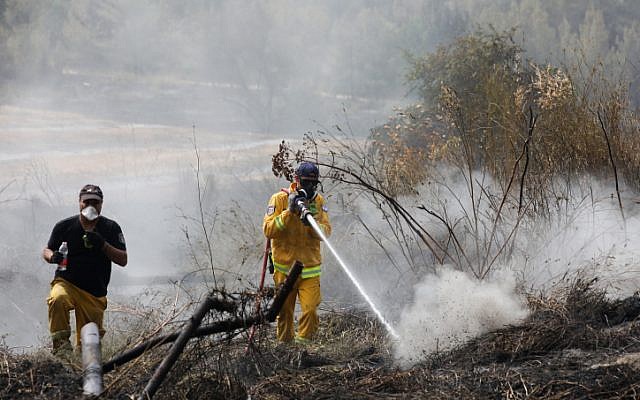 Les sapeurs-pompiers éteignent les restes d'un feu dans le kibboutz Harel, le 24 mai 2019 (Crédit : Noam Revkin Fenton/Flash90)
