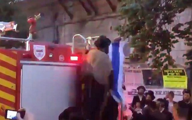 Une capture d'écran d'un homme ultra-orthodoxe dans le quartier de Mea Shearim à Jérusalem arrachant un drapeau israélien d'un camion de pompiers, le 9 mai 2019. (Capture d'écran : Twitter) Une capture d'écran d'un homme ultra-orthodoxe dans le quartier de Mea Shearim à Jérusalem arrachant un drapeau israélien d'un camion de pompiers, le 9 mai 2019. (Capture d'écran : Twitter)