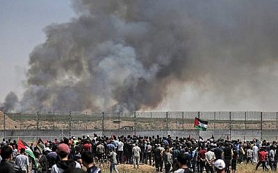 Des manifestants palestiniens participent à des émeutes le long de la barrière de sécurité à l'est de la ville de Gaza alors que de la fumée s'envole dans le ciel. L'incendie a été provoqué par un engin incendiaire attaché à un cerf volant envoyé de l'autre côté de la frontière vers Israël depuis la bande de Gaza, le 15 mai 2019. (Crédit : MAHMUD HAMS / AFP) Des manifestants palestiniens participent à des émeutes le long de la barrière de sécurité à l'est de la ville de Gaza alors que de la fumée s'envole dans le ciel. L'incendie a été provoqué par un engin incendiaire attaché à un cerf volant envoyé de l'autre côté de la frontière vers Israël depuis la bande de Gaza, le 15 mai 2019. (Crédit : MAHMUD HAMS / AFP)