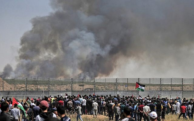 Des manifestants palestiniens participent à des émeutes le long de la barrière de sécurité à l'est de la ville de Gaza alors que de la fumée s'envole dans le ciel. L'incendie a été provoqué par un engin incendiaire attaché à un cerf volant envoyé de l'autre côté de la frontière vers Israël depuis la bande de Gaza, le 15 mai 2019. (Crédit : MAHMUD HAMS / AFP) Des manifestants palestiniens participent à des émeutes le long de la barrière de sécurité à l'est de la ville de Gaza alors que de la fumée s'envole dans le ciel. L'incendie a été provoqué par un engin incendiaire attaché à un cerf volant envoyé de l'autre côté de la frontière vers Israël depuis la bande de Gaza, le 15 mai 2019. (Crédit : MAHMUD HAMS / AFP)
