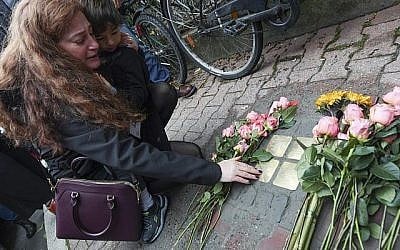 Mandy Eisemann de Dickerson, Maryland, avec son fils Levi (4), de proches de la famille Cohn, dépose des fleurs aux quatre 
"Stolpersteine" (pierres chancelantes) pour Karolina Cohn et sa famille à Frankfurt, Allemagne, le 13 novembre 2017. (Arne Dedert/dpa via AP)