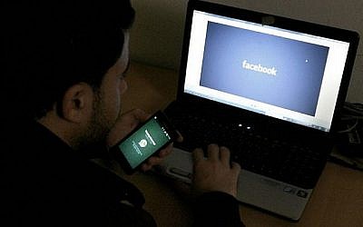 Image d'un homme devant un ordinateur avec le logo Facebook, le 26 février 2014 (Abed Rahim Khatib/Flash90)