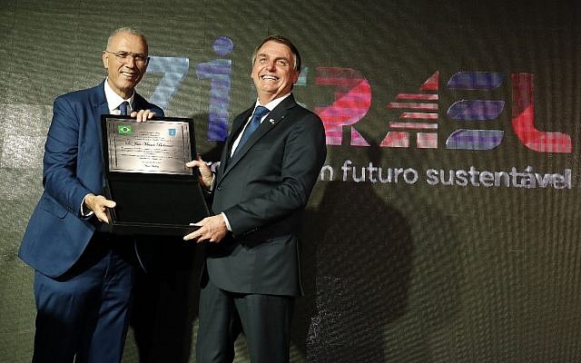 Le président brésilien Jair Bolsonaro (D) reçoit une plaque marquant le 71e anniversaire de la naissance d'Israël lors d'un événement à l'ambassade israélienne à Brasilia, le 22 mai 2019 (Crédit : autorisation de l'ambassade israélienne à Brasilia)