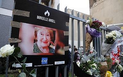 Une photo de Mireille Knoll, survivante de la Shoah, assassinée, et des fleurs sont placées sur la clôture entourant son immeuble à Paris, le 28 mars 2018. (Crédit : François Guillot / AFP)