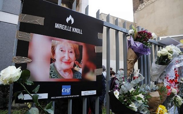 Une photo de Mireille Knoll, survivante de la Shoah, assassinée, et des fleurs sont placées sur la clôture entourant son immeuble à Paris, le 28 mars 2018. (Crédit : François Guillot / AFP) Une photo de Mireille Knoll, survivante de la Shoah, assassinée, et des fleurs sont placées sur la clôture entourant son immeuble à Paris, le 28 mars 2018. (Crédit : François Guillot / AFP)