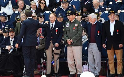 Le président français Emmanuel Macron salue des vétérans américains après leur avoir remis la Légion d'Honneur au cimetière américain de Coleville sur mer, le 6 juin 2019. (Crédit : Damien MEYER / AFP)
