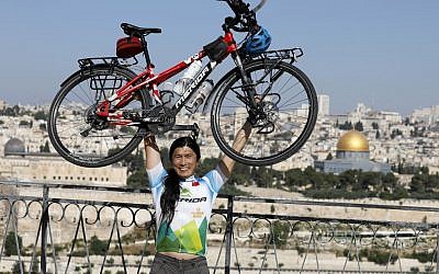 Le cycliste taïwanais qui fait le tour du monde, pose avec son vélo sur le mont des Oliviers, qui surplombe la Vieille Ville de Jérusalem, le 10 juin 2019. (Crédit : MENAHEM KAHANA / AFP)
