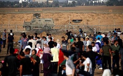 Un Palestinien lance des objets avec une fronde de l'autre côté de la clôture frontalière avec Israël lors d'affrontements avec les soldats israéliens, à l'est de Khan Yunis, dans la bande de Gaza, le 21 juin 2019 (Crédit :  Said KHATIB / AFP)