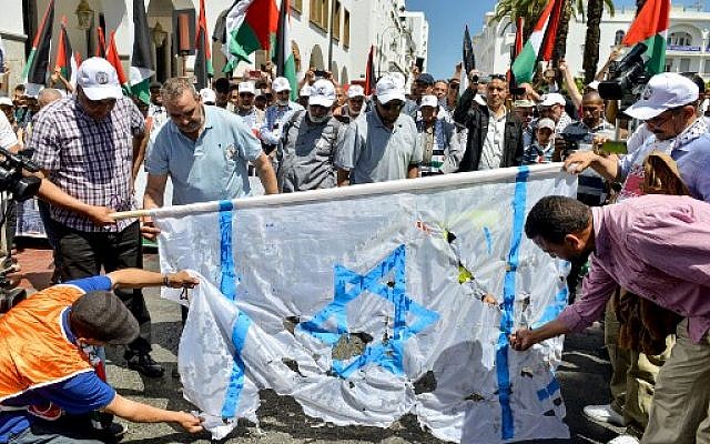 Des manifestants déchirent un drapeau israélien lors d'une manifestation à Rabat, la capitale marocaine, le 23 juin 2019 contre la conférence économique organisée à Bahreïn par les États-Unis. (Crédit photo : AFP)