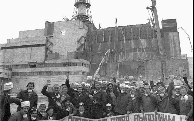 Les ouvriers qui ont construit le sarcophage de ciment recouvrant le réacteur n° 4 de Tchernobyl posent avec une banderole qui dit : "Nous exécuterons l'ordre du gouvernement" à l'été 1986 sur le chantier inachevé. (AP Photo/ Volodymyr Repik)