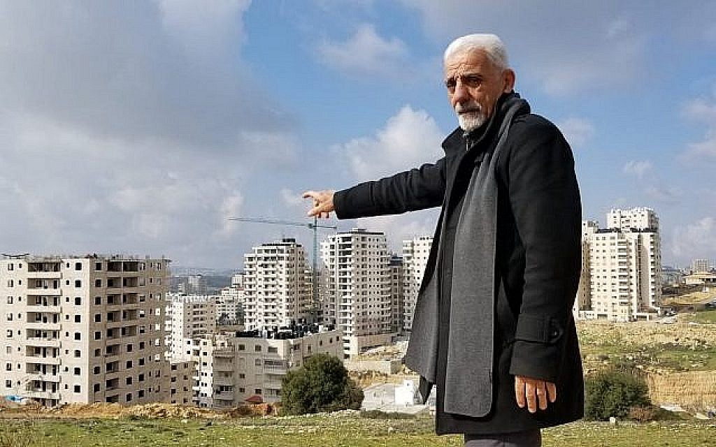 Munir Zughayer, un activiste qui dirige un comité qui se plaint souvent de la situation des services à Kafr Aqab auprès de la municipalité de Jérusalem, pointe du doigt un certain nombre de bâtiments construits en violation de la réglementation le 20 février 2019. (Crédit : Adam Rasgon / Times of Israël)